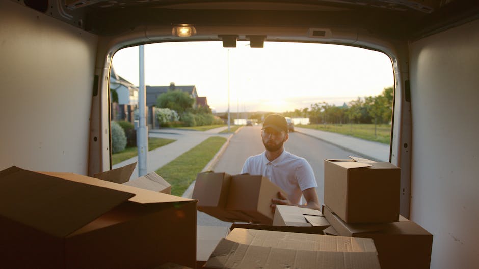 A man and a woman are engaged in a home relocation process involving furniture transport and packing during a moving service by Man and Van Morden. The man is wearing a white t-shirt, black cap, and g